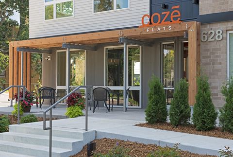 the entrance to coze flats with tables and chairs outside of the building