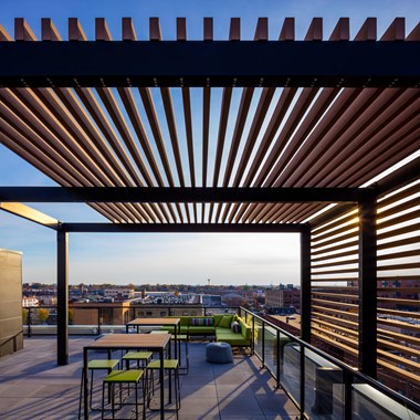 a rooftop terrace with tables and chairs and a pergola on top of it