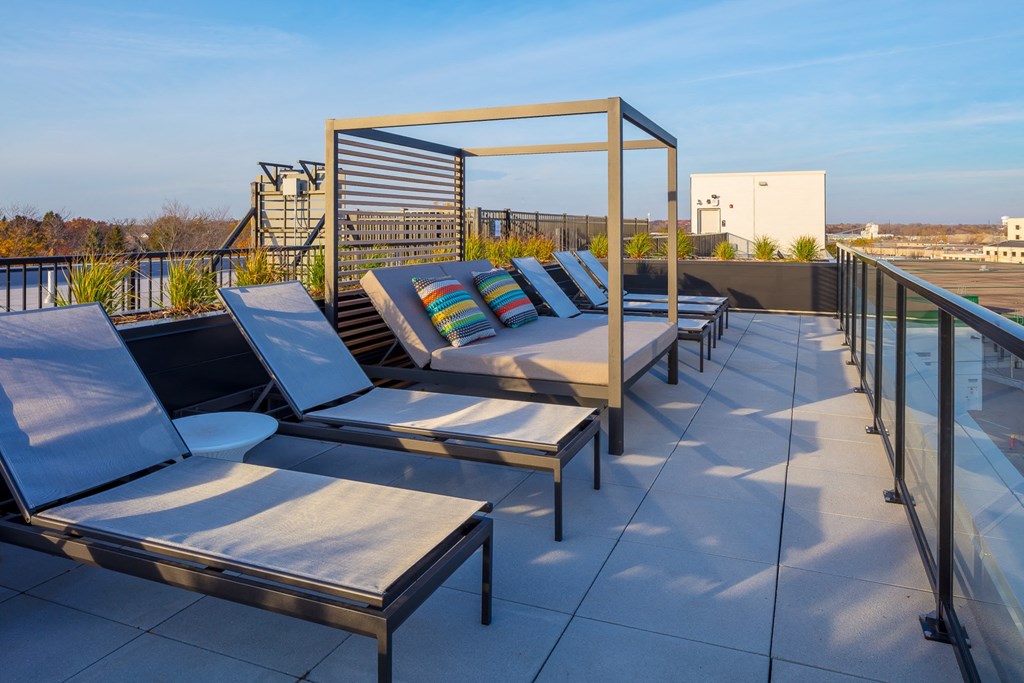 a rooftop deck with lounge chairs and a pergola