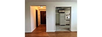 an open doorway into a kitchen and a living room with a refrigerator