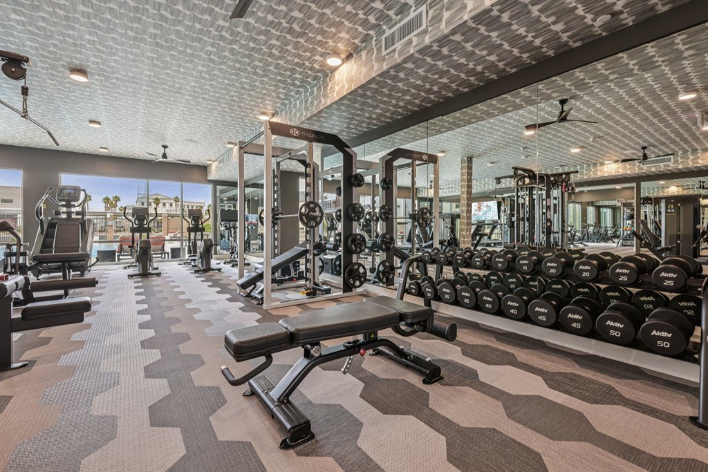 A gym with a variety of equipment including dumbbells and weight machines.