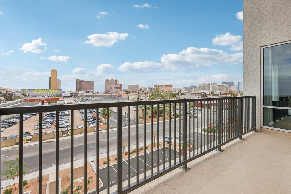A balcony with a view of a parking lot and buildings.