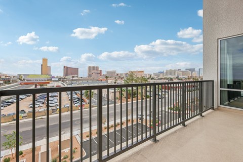 A balcony with a view of a parking lot and buildings.