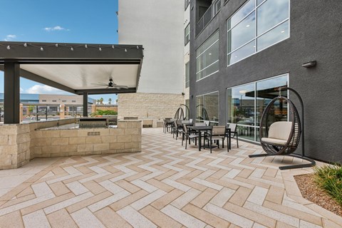 A patio area with a table and chairs and a building in the background.
