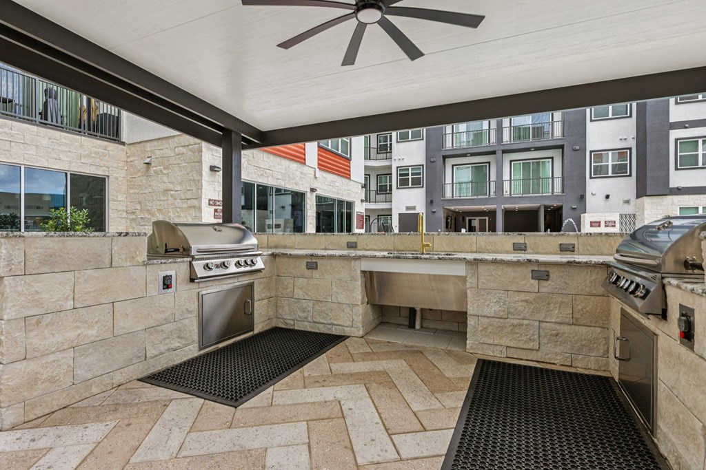A patio with a BBQ grill and a fan.