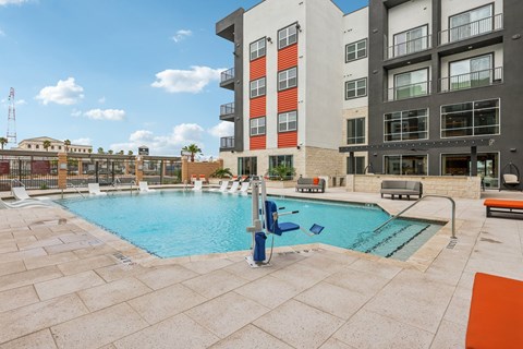 A large swimming pool in front of a multi-story apartment building.