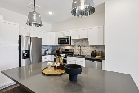 A modern kitchen with a stainless steel refrigerator and a black pot on the counter.