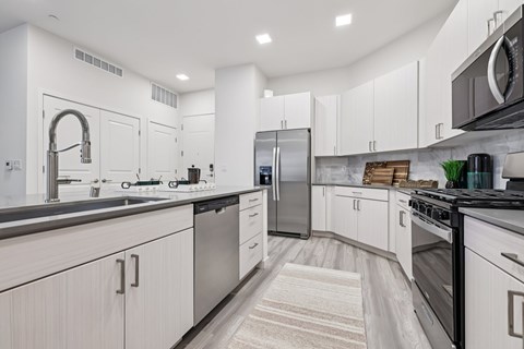 A modern kitchen with white cabinets and stainless steel appliances.