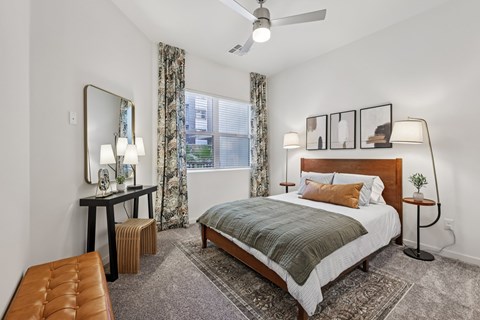 A bedroom with a large bed, a bench, and a mirror.