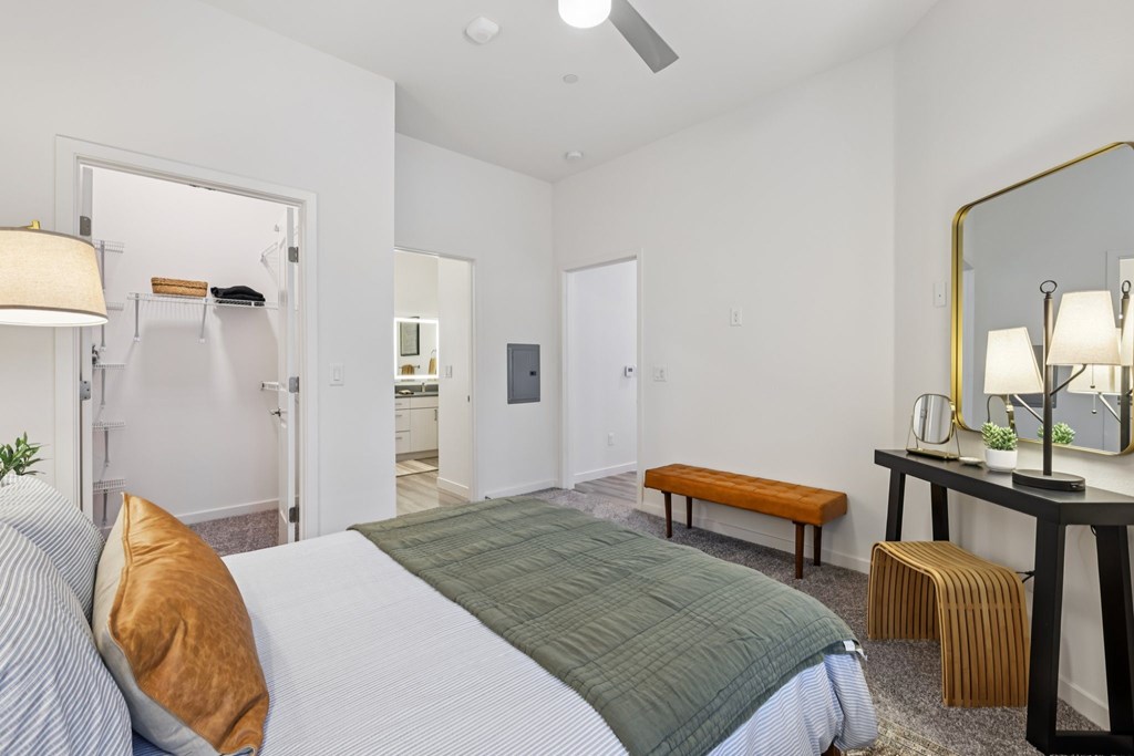 A bedroom with a bed, a bench, and a mirror.