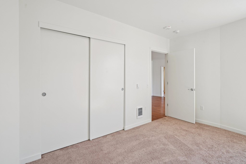 A white room with a carpeted floor and three doors.