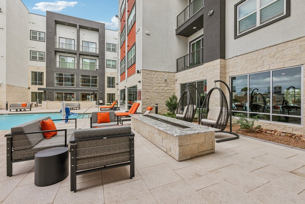 A patio with a pool and chairs.