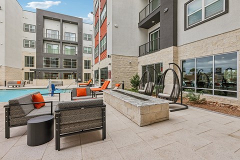 A patio with a pool and chairs.