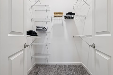 A white closet with shelves and clothes.
