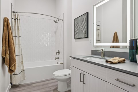 A white bathroom with a towel hanging on the shower rod.