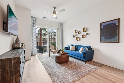 A living room with a blue couch and a flat screen TV mounted on the wall.