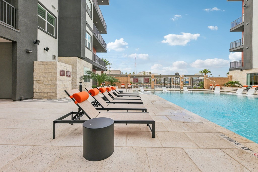 A poolside area with sun loungers and a trash bin.
