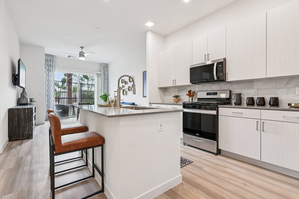 A modern kitchen with white cabinets and a wooden floor.