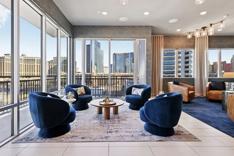 A living room with blue chairs and a view of the city.