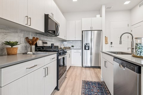 A modern kitchen with white cabinets and stainless steel appliances.