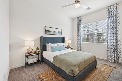 A bedroom with a bed, nightstand, and window.