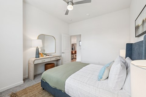 A bedroom with a bed, desk, and mirror.