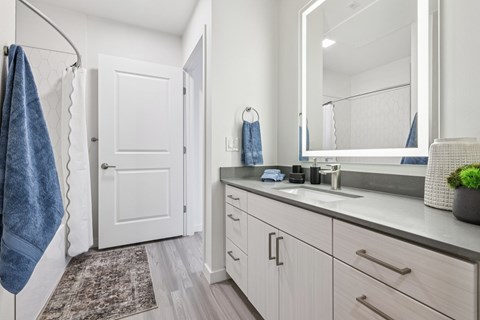 A bathroom with a white door, a mirror, and a sink.