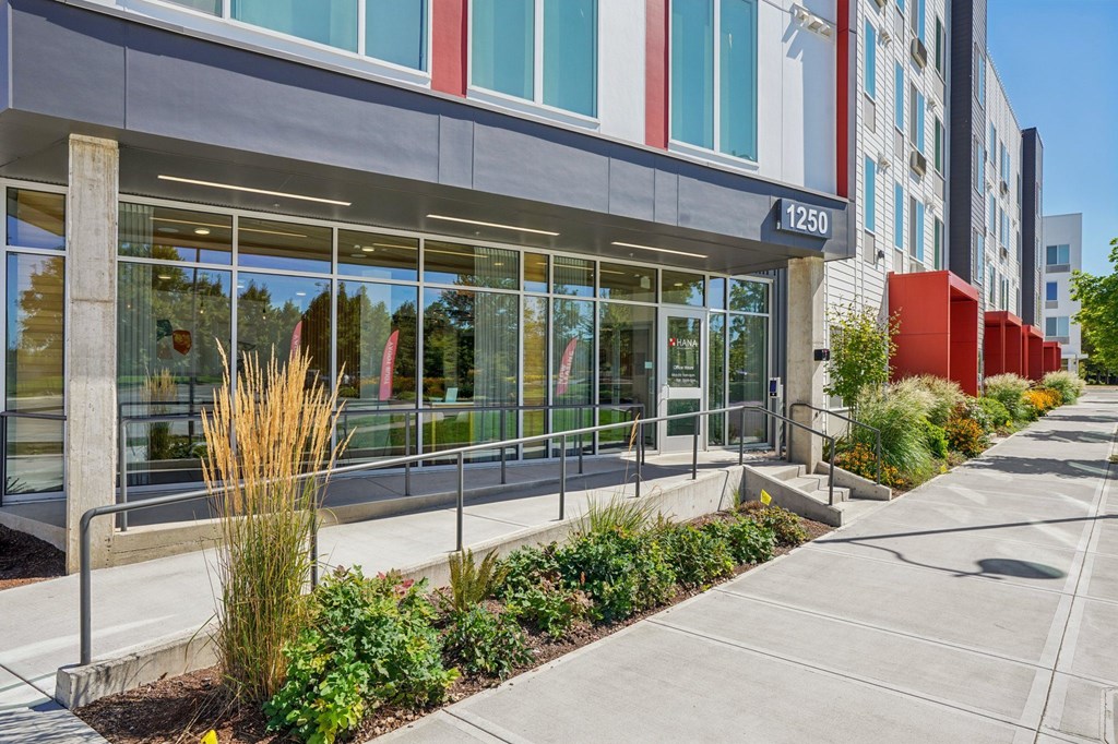 A modern building with a glass facade and a red wall on the side.