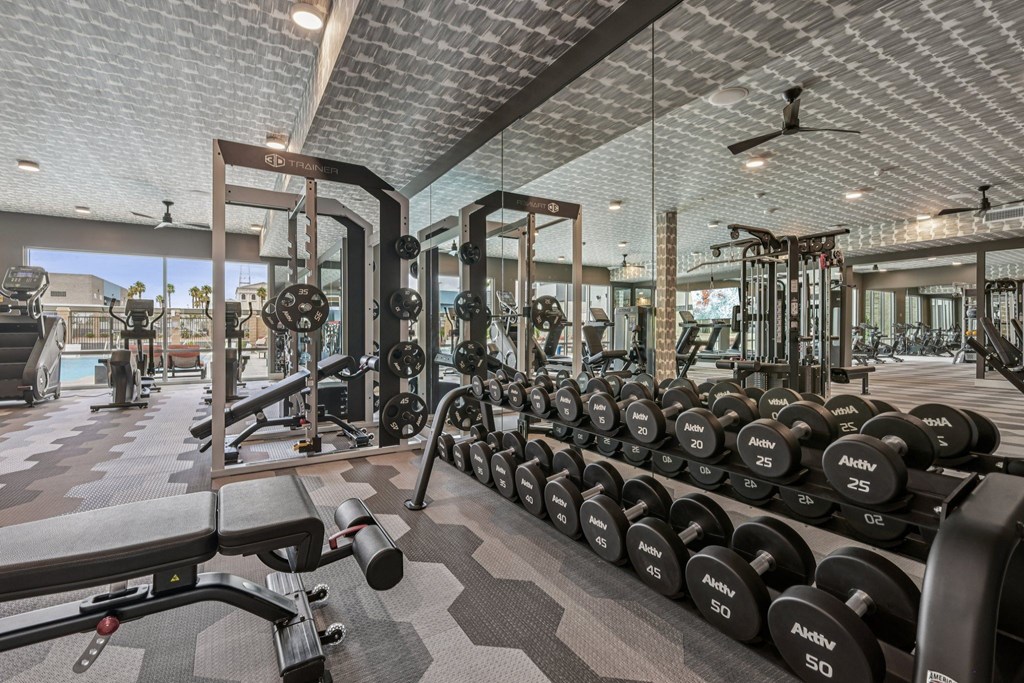 A gym with a variety of equipment including dumbbells and weight machines.