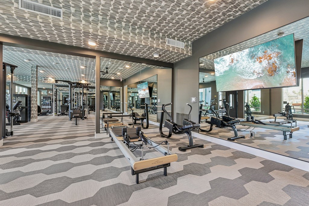 A gym with a variety of equipment and a ceiling with a patterned design.