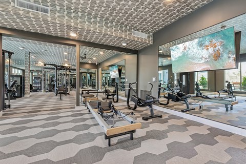 A gym with a variety of equipment and a ceiling with a patterned design.