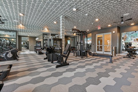 A gym with a variety of equipment and a patterned ceiling.