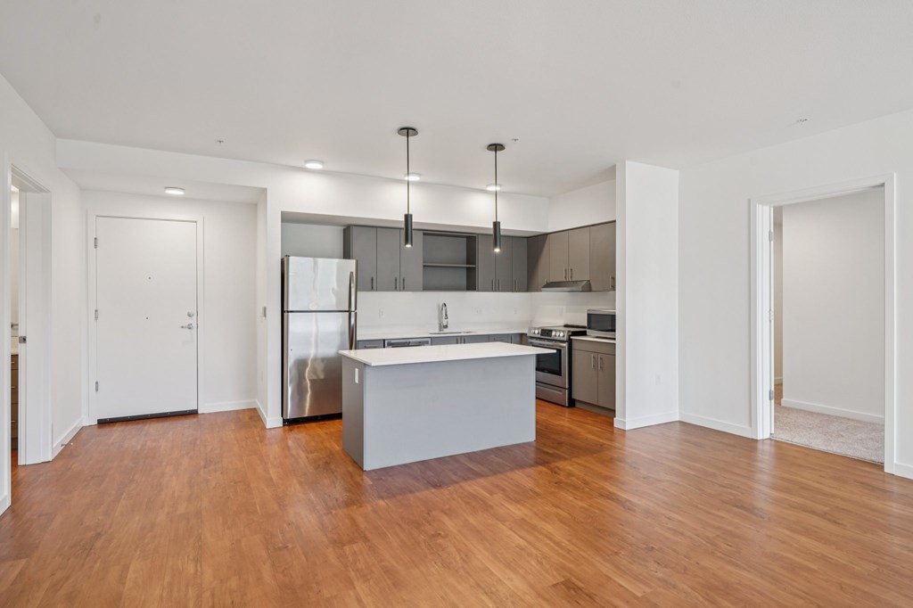 A kitchen with a white island and wooden floors.