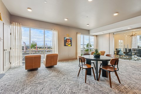 A room with a round table and chairs with a view of the outside.
