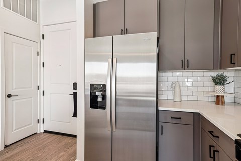 A stainless steel refrigerator in a kitchen with white cabinets.