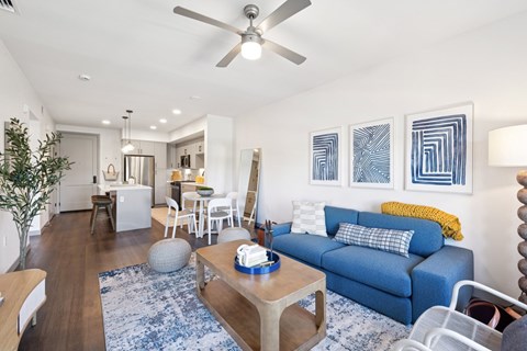 A living room with a blue couch and a ceiling fan.