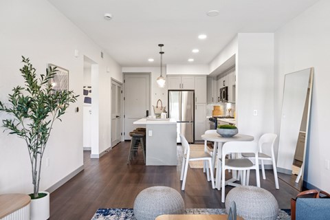 A modern kitchen with white cabinets and a dining area with white chairs.