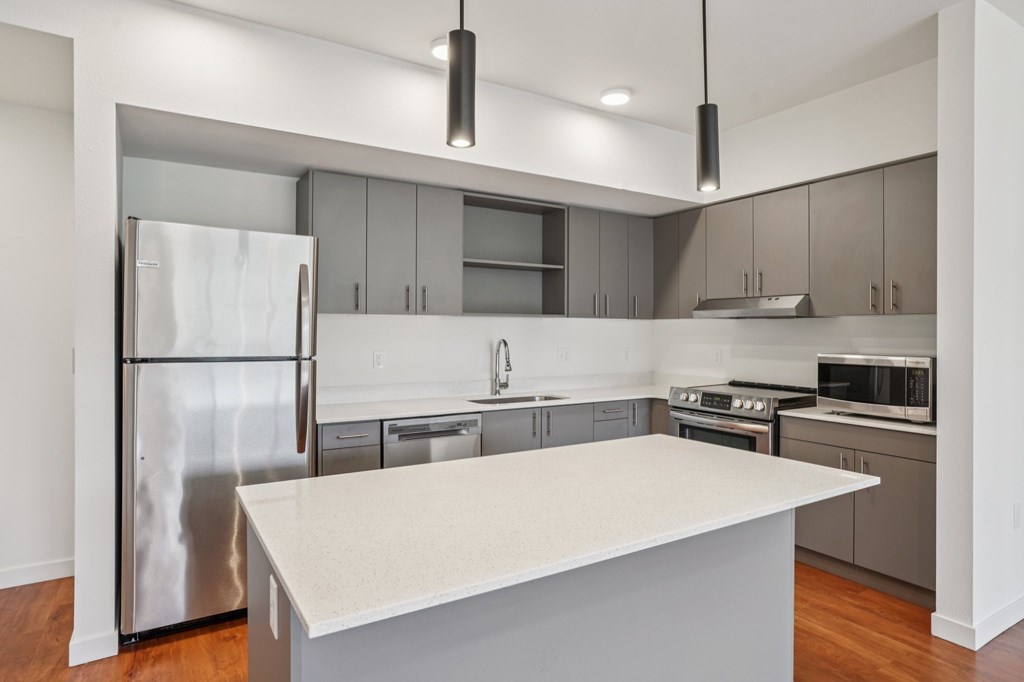 A modern kitchen with a stainless steel refrigerator and a white island.