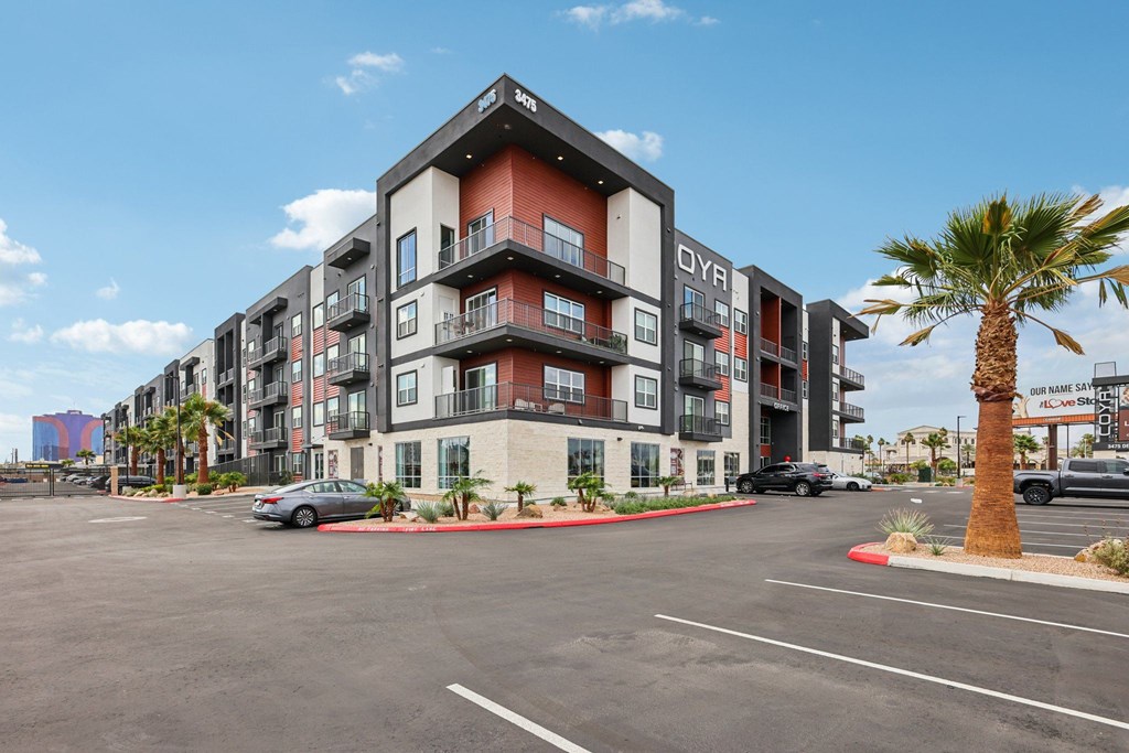 A modern apartment complex with a parking lot in front.
