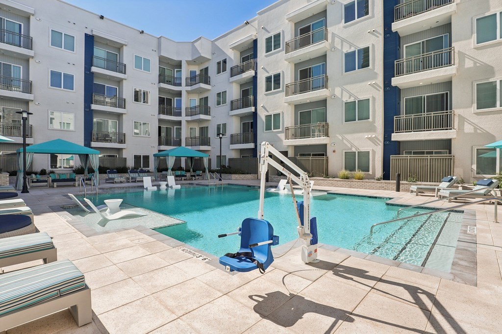 A swimming pool with a diving board in front of apartment buildings.