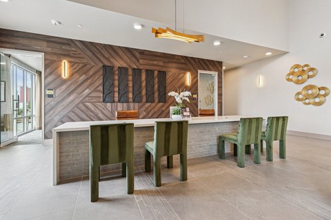 A modern interior with a wooden panelled wall and green chairs.