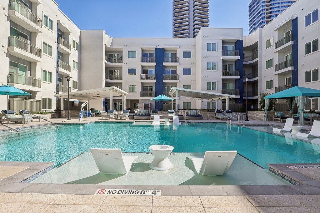 A pool surrounded by white chairs and umbrellas with a sign that says "No Diving".