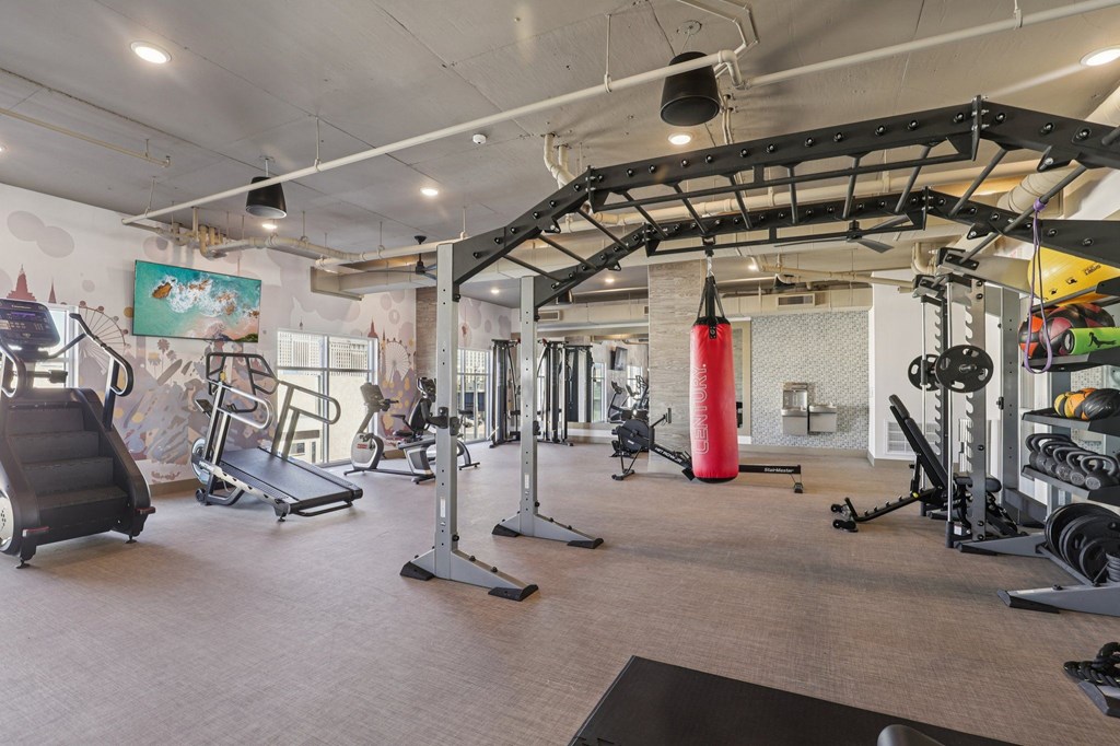 A gym with a variety of equipment including treadmills, weights, and exercise machines.