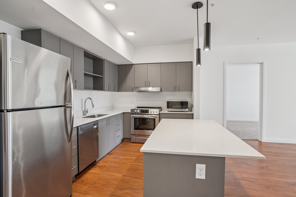 A modern kitchen with stainless steel appliances and wooden floors.