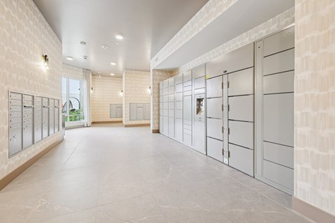 A long hallway with a row of lockers on the left and a row of doors on the right.