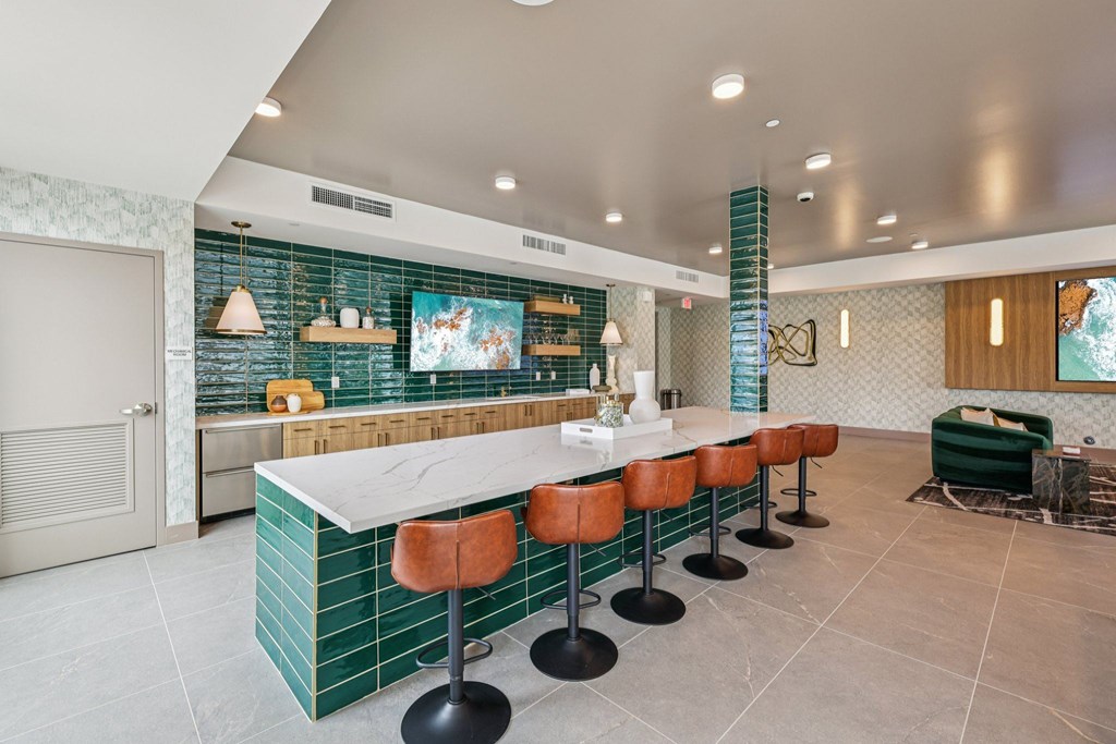 A kitchen with green tiles and a white counter.