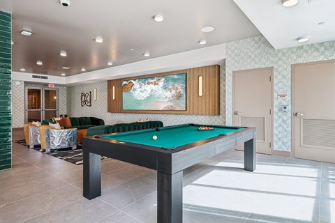 A pool table in a room with a green wall and a painting on the wall.