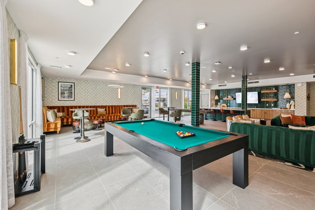 A billiard table is in the middle of a room with a green cloth on it.