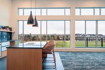 A desk with large windows and a view of a green space