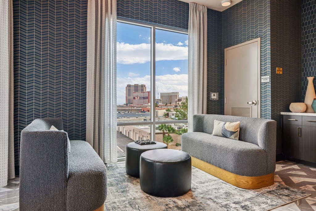 A living room with a grey sofa, a grey armchair, and a black ottoman.